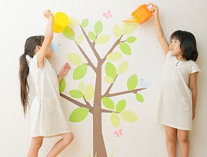 二人の子供が壁の木の絵に水をあげている